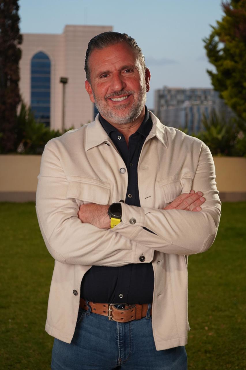 Formal portrait of Roberto Arzú in a navy polo shirt and cream jacket