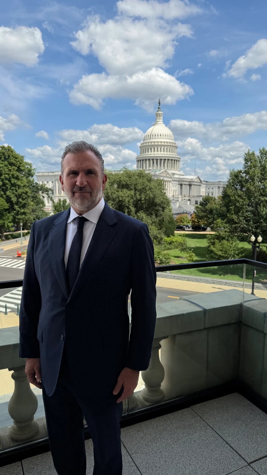 Roberto Arzú standing on a terrace with the United States Capitol dome behind him