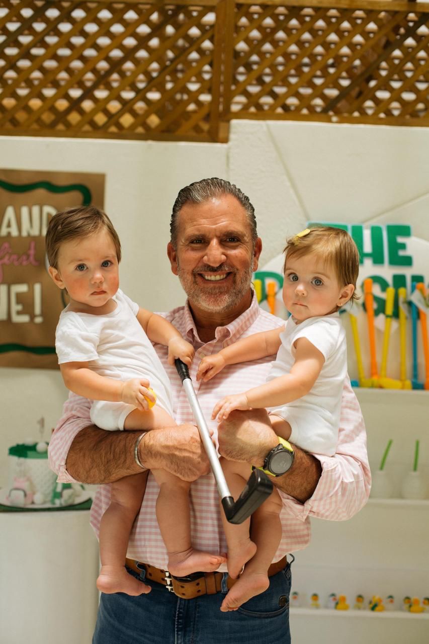 Roberto Arzú holding his two young granddaughters at a family celebration