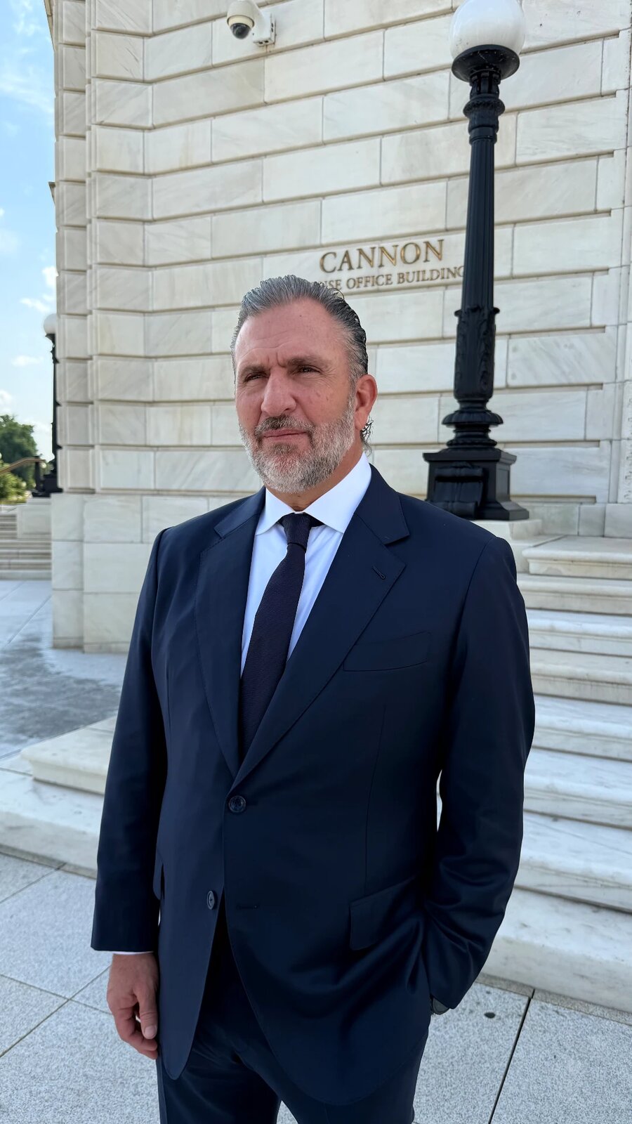 Roberto Arzú in a dark suit outside the Cannon House Office Building in Washington, D.C.